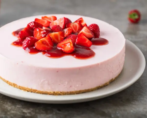 Cheesecake rosa con fragole fresche e salsa, un dolce delizioso, perfetto per ogni occasione.