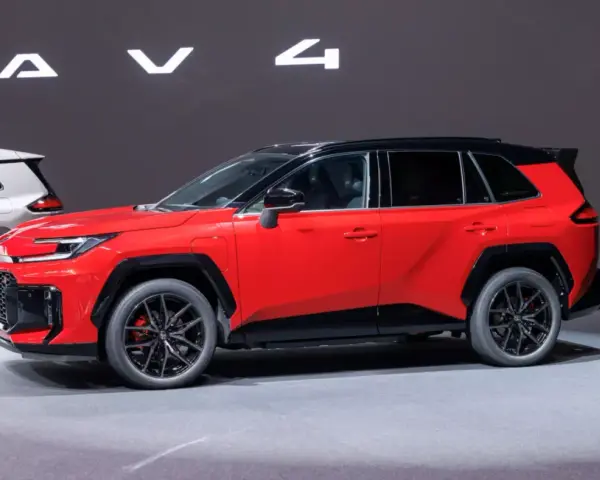 Czerwony, tani SUV z czarnym dachem i felgami, prezentowany na wystawie obok białego modelu.