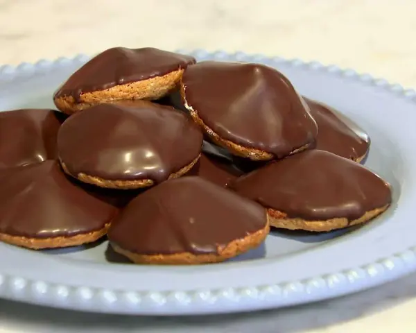 En hög med chokladöverdragna biskvier på en ljusblå tallrik. Perfekt för ett enkelt biskvier recept.