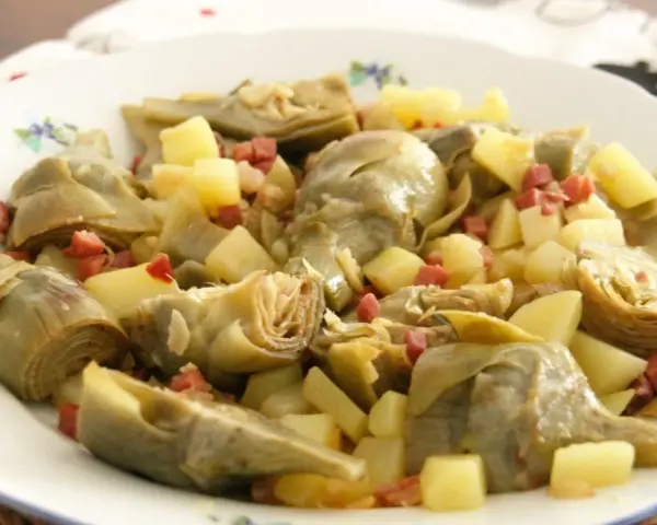 Plato de alcachofas tiernas y trocitos de jamón serrano, un clásico delicioso.