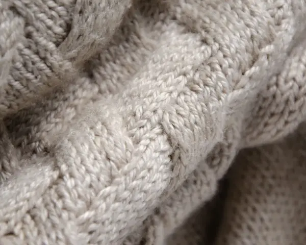 Tessuto a maglia grossa color crema, con un motivo a trecce che ricorda la morbidezza della flanella.