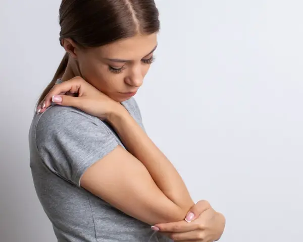 Mujer con dolor de codo, su piel con textura granulada se ve tensa.