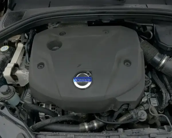 Silnik D4 Volvo pod czarną osłoną z niebieskim logo. Widać fragmenty przewodów i zbiornik płynu.