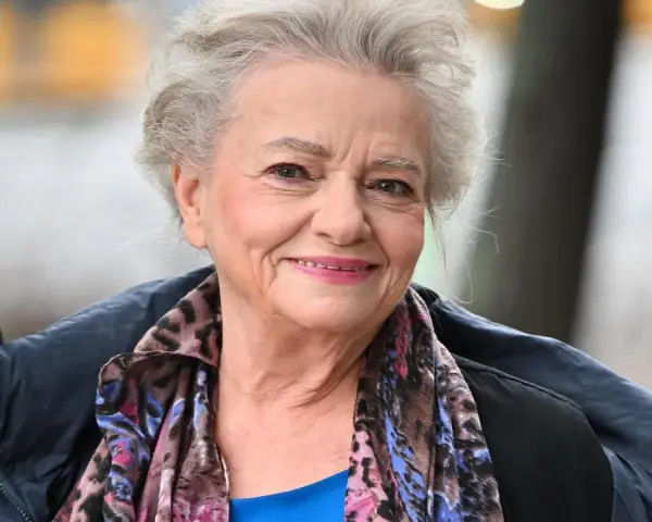 Uśmiechnięta Anna Seniuk, ikona polskich filmów, seriali i programów, w kolorowym szalu i granatowej kurtce.