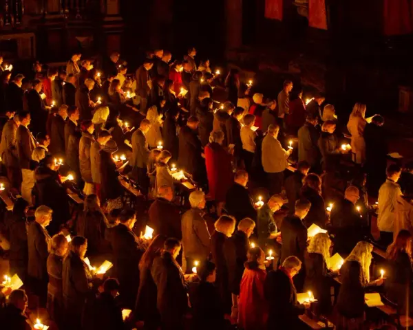 A solemn vigil unfolds as a congregation holds candles, their faces illuminated by the soft glow.