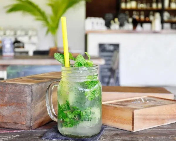 Erfrischender Mojito mit Minze und Eis in einem Glas. So trinkt man Rum an einem heißen Tag.