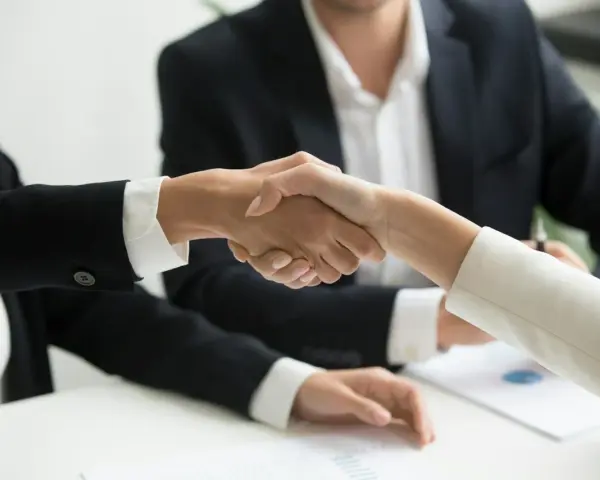 Poignée de main entre deux personnes en costume, symbolisant un accord ou un changement de dirigeant.