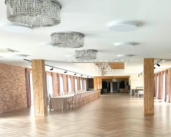Elegancka sala weselna z kryształowymi żyrandolami i drewnianymi elementami. Zastanawiasz się, ile kosztuje wesele na 100 osób w takim miejscu?