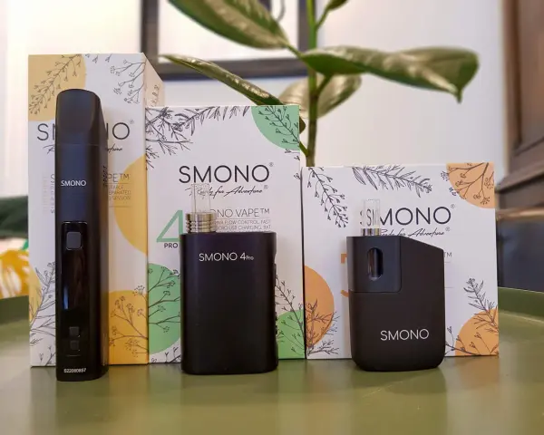 Tres vaporizadores negros de la marca Smoant, junto a sus cajas con diseños botánicos, listos para la aventura.