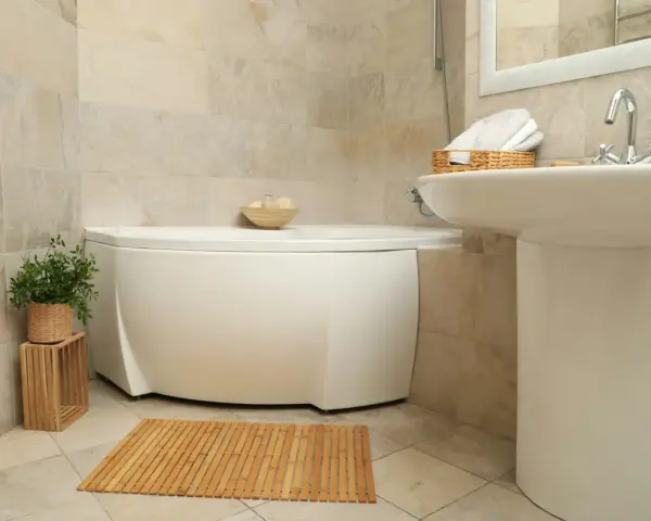 Ett badrum med hörnbadkar, handfat och en trämatta. Perfekt för liten toalett inspiration med naturliga material.