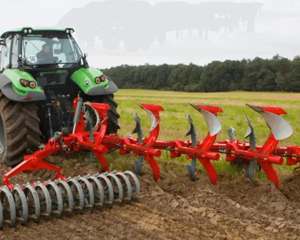 Zielony traktor z pługiem obrotowym pracuje na polu, przygotowując ziemię do siewu.