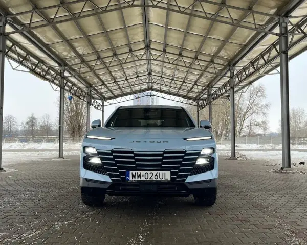 Jasny Jetour Dashing z charakterystycznym grillem i światłami LED stoi pod zadaszeniem.