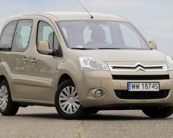 Beżowy Citroen Berlingo 1.6 HDI na drodze, z zielonym polem w tle.