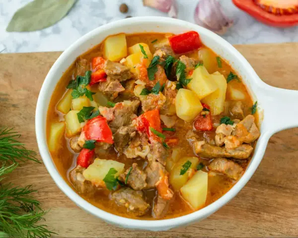 Aksamitna, aromatyczna najlepsza zupa gulaszowa z kawałkami mięsa, ziemniaków i papryki, posypana świeżą natką pietruszki.