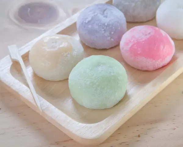 Kolorowe mochi, czyli japońskie ciastka ryżowe, na drewnianej tacy. Zastanawiasz się mochi co to? To pyszna, miękka przekąska!