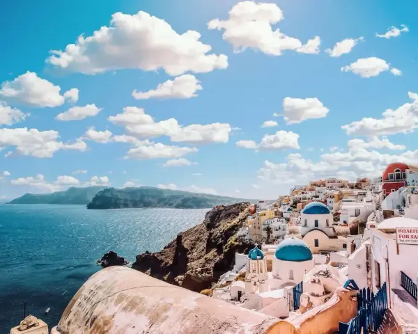 Santorini, Grecja. Ile się leci do raju? Białe domki z niebieskimi kopułami na tle błękitnego morza i nieba.