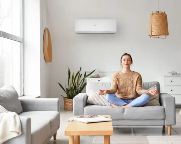 Donna medita in un soggiorno confortevole, con un condizionatore d'aria inverter che garantisce un clima ideale per il relax.