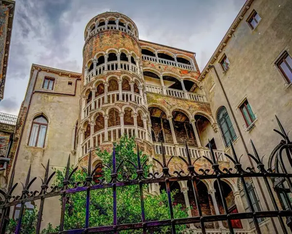 La scala chiocciola di Venezia, con i suoi archi e balconi, si erge maestosa tra antichi palazzi.