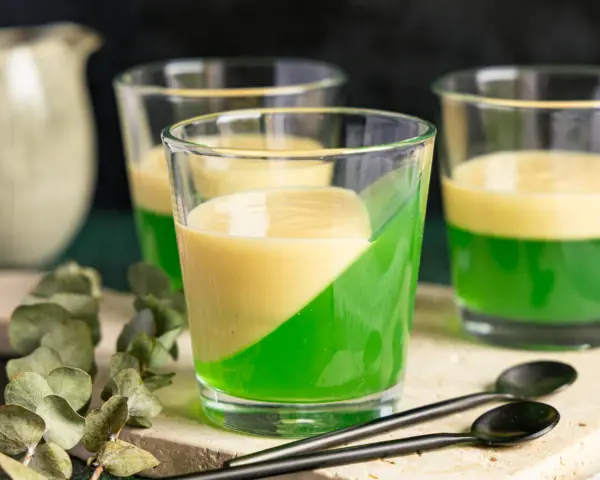 Zwei Schichten Wackelpudding, grün und gelb, in Gläsern. Perfekt, um Wackelpudding selber machen zu lernen und zu genießen.