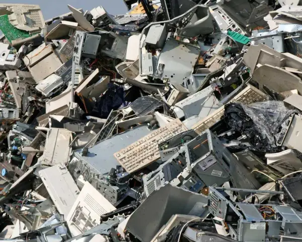 Góra starych komputerów, monitorów i klawiatur. To widok na odpady przemysłowe, które czekają na recykling.