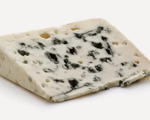 Un trozo de queso azul con vetas oscuras, un queso que huele mal pero es delicioso.