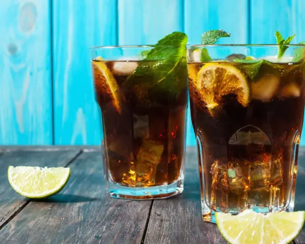 Dwa orzeźwiające drinki z rumem, lodem, limonką i miętą na drewnianym blacie. Idealny dobry drink z rumem na upalne dni.