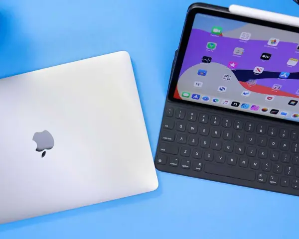 Geschlossenes MacBook neben einem geöffneten iPad Pro mit Tastatur und Apple Pencil.