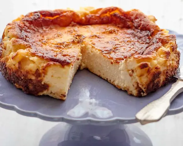 Tarta de queso La Viña, dorada y cremosa, servida en un plato morado.