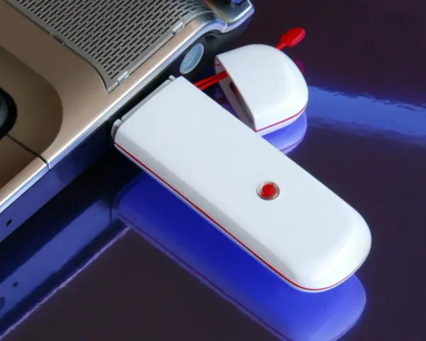 Biały modem USB podłączony do laptopa, umożliwiający komórkową transmisję danych.
