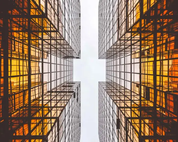 Looking up between four golden glass buildings, the architecture forms a cross shape, resembling a modern church.