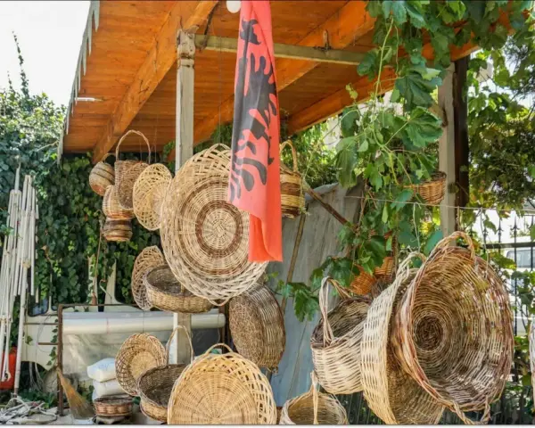 Wiele koszy z wikliny wisi pod zadaszeniem, obok albańskiej flagi. Czy Albania jest bezpieczna dla kobiet? Tak, to piękny kraj.