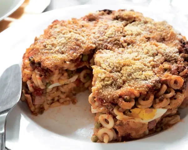 Un invitante anelletti al forno, con strati di pasta, sugo, piselli e uova sode, ricoperto da pangrattato dorato.
