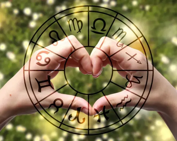 Dłonie tworzą serce w okręgu zodiaku, gdzie widnieją symbole, w tym te z najtrudniejszych znaków zodiaku.