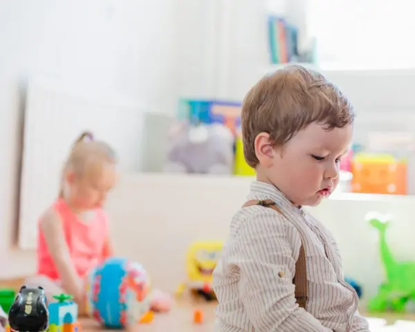 Chłopiec w szelkach i dziewczynka bawią się zabawkami. Zastanawiasz się, jak zapisać dziecko do żłobka?