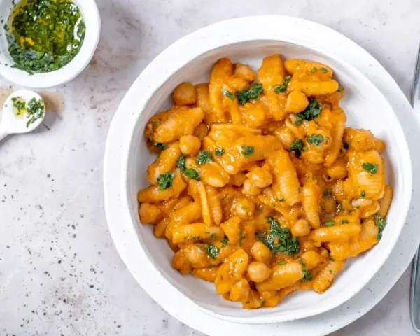 Herzhaftes Pasta e Ceci mit Kichererbsen in cremiger Sauce, garniert mit frischer Petersilie. Daneben eine kleine Schale mit Kräuteröl.