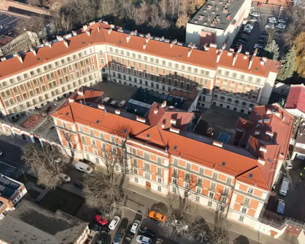 Widok z lotu ptaka na budynki więzienia aś montelupich. Czerwone dachy, białe fasady, dziedziniec z samochodami i drzewami.