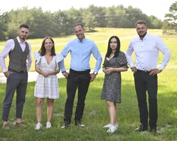 Uczestnicy programu "Rolnik szuka żony 10" pozują na tle zielonej łąki.