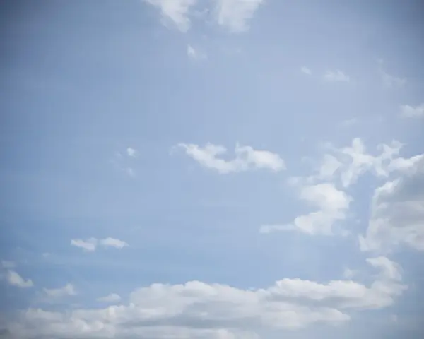Jasne niebo z chmurami, efekt winietowania przyciemnia brzegi kadru, tworząc wrażenie głębi.