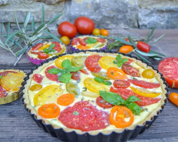 Eine herzhafte Tomaten Quiche mit bunten Tomatenscheiben und frischem Basilikum, garniert mit Lavendelblüten.