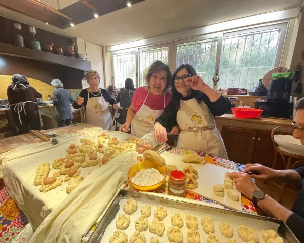 Donne sorridenti preparano impasti per piatti tipici di Perugia, con uova e pane intrecciato.