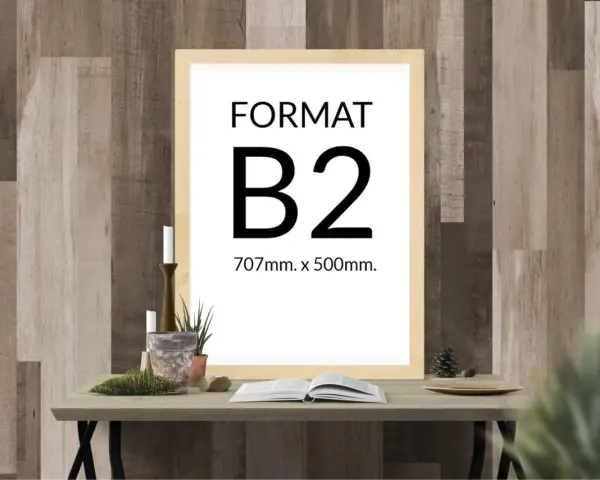 Ramka z napisem "FORMAT B2 707mm. x 500mm." na tle drewnianej ściany. Na stole obok książka i świece.