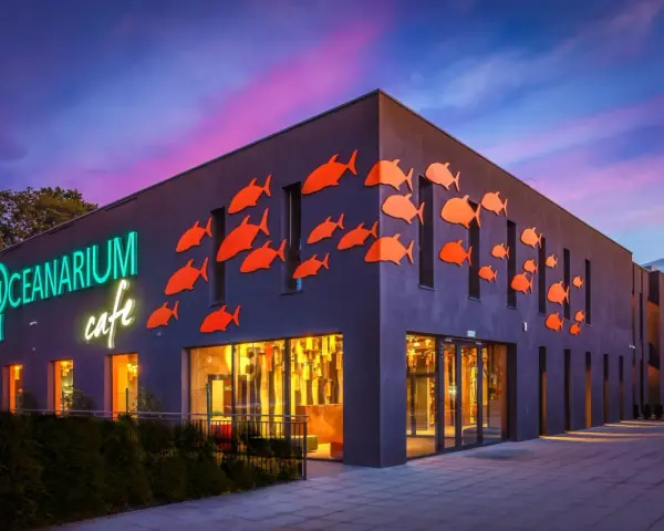 Oceanarium w Międzyzdrojach, z neonowym napisem i pomarańczowymi rybkami na fasadzie, to świetne miejsce na rodzinne atrakcje dla dzieci.