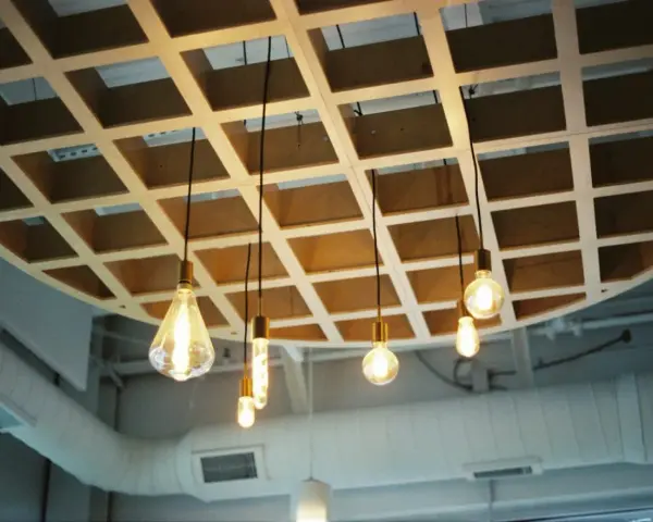 Drewniana kratownica sufitowa, idealna do pokazania, jak zrobić podwieszany sufit. Wiszące żarówki tworzą ciepłą atmosferę.