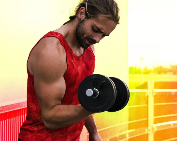 Homme musclé faisant un exercice pour muscler les bras avec un haltère.