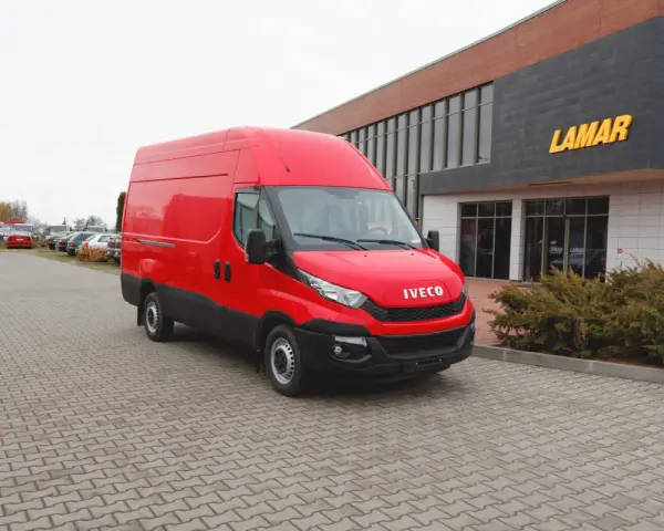 Czerwony bus Iveco na parkingu przed budynkiem z napisem LAMAR.