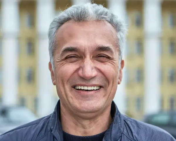 Uśmiechnięty mężczyzna z siwymi włosami, który wygląda jak typowy boomer. Co to znaczy? To ktoś z pokolenia wyżu demograficznego, często kojarzony z pewnymi wartościami i stylem życia.