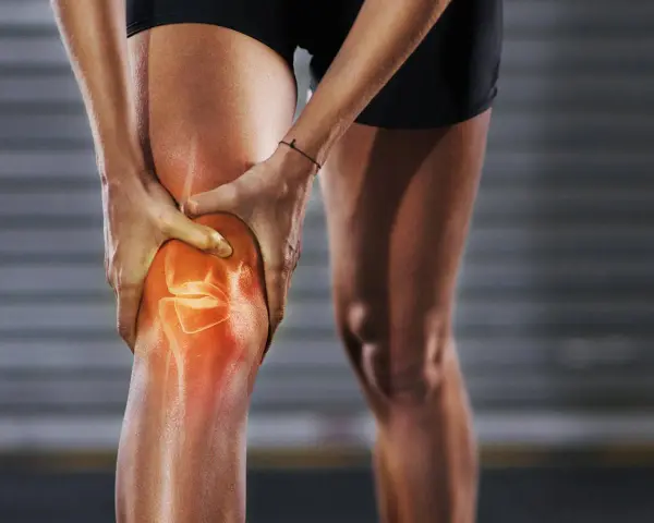 Person hält schmerzendes, dickes Knie. Was tun bei Knieproblemen? Rote Hitze zeigt Entzündung.