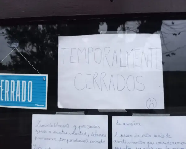 Cartel de "CERRADO" y otro escrito "TEMPORALMENTE CERRADOS" en la ventana de un bar restaurante.