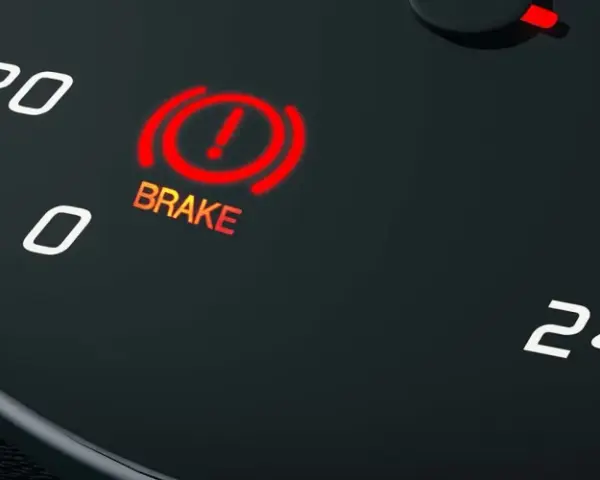 The car's dashboard shows the red brake light on, indicating a potential issue.