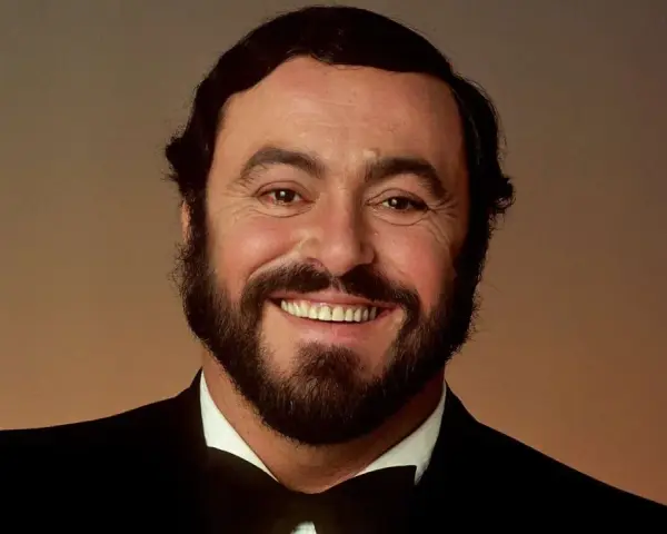 Portrait souriant de Luciano Pavarotti, le célèbre chanteur rock italien, en costume noir et nœud papillon.